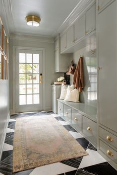 a large rug in the middle of a room with white cupboards and drawers on both sides