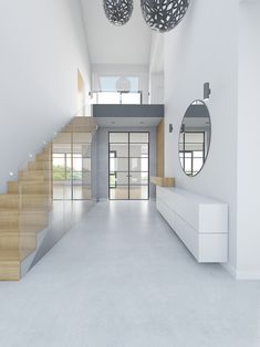 an empty white room with wooden stairs and round mirrors hanging from the ceiling above it