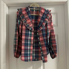 a red and blue plaid jacket hanging on a white door