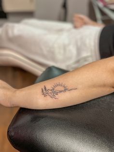 a woman with a tattoo on her arm sitting in a chair next to a bed