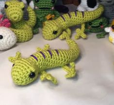 several crocheted lizards and stuffed animals on a table