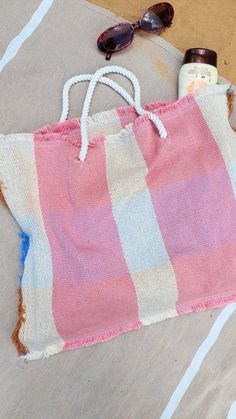 a pink and white striped bag sitting on top of a beach towel next to sunglasses