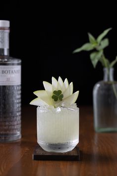 a small glass vase with a flower in it sitting on a table next to a bottle