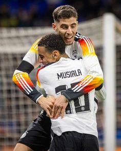 two soccer players hugging each other on the field