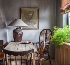 a table with two chairs and a lamp on top of it in front of a window