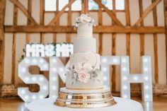 a white and gold wedding cake sitting on top of a table in front of a sign