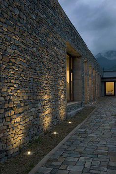 an outdoor area with stone walls and lights on the walkway, as seen at night