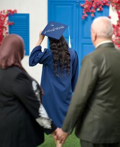 a woman in a blue graduation cap and gown is walking towards another person with her hand on her head