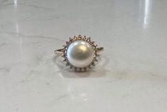 Cleopatra, Princess Di, Jackie O - all loved pearls. The classic gem for classic beauties. This stunning ring features a freshwater pearl encircled by lustrous crystals. Available in silver or gold. Adjustable, size 5-8 PRODUCT DETAILS: 10mm AAA freshwater button iridescent pearl Luster - High Setting: sterling silver or 14kt gold plated with crystal mount Size: Adjustable, Size 5-8 Materials: Freshwater Pearl and .925 sterling silver coated in rhodium or 14kt gold plated over .925 sterling silver Timeless Akoya Pearl Round Rings, Timeless Akoya Pearl Ring, Elegant Oval Pearl Drop Rings, Elegant Oval Rings With Pearl Drop, Pearl Jewelry With Prong Setting, Timeless Round Pearl Ring, Pearl Charm Promise Ring, Heirloom Pearl Ring With Gemstone, Diamond Pearl Ring With Pearl Drop