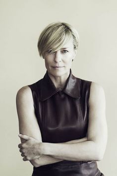 a black and white photo of a woman wearing a leather dress with her arms crossed