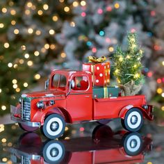 a red toy truck with presents on the back and christmas tree in the back sitting next to it