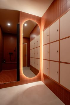 a bathroom with a large mirror and tiled walls, along with red tile flooring