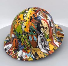 a colorful helmet is sitting on a white surface and it has many different colored images all over it