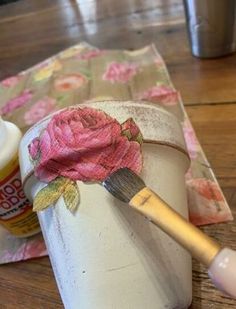 a paintbrush is being used to paint a flower on a white bucket with pink flowers