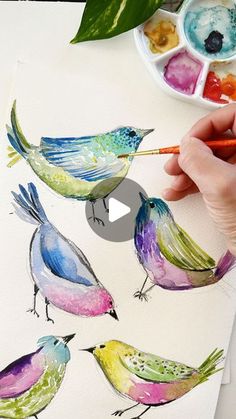 a person is painting birds with watercolors on paper