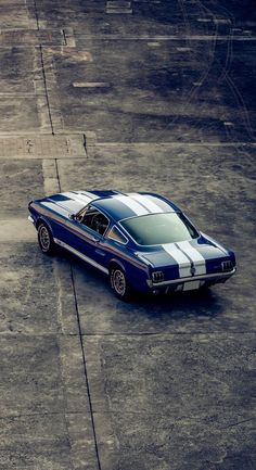 a blue and white mustang sitting on top of an airport tarmac with no one around it