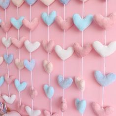 a pink wall with hearts hanging from it's sides and some toys in the background