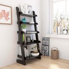 a black book shelf sitting on top of a hard wood floor next to a window