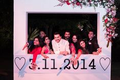 a group of people posing for a photo in front of a sign with hearts and flowers