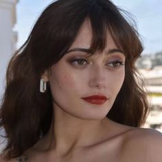 a close up of a woman with dark hair and red lipstick wearing large hoop earrings