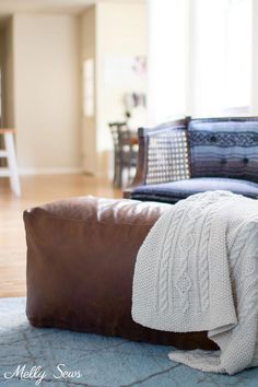 a brown leather chair with a white blanket on it and a blue rug in the background