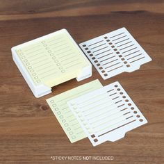 three sticky notes sitting on top of a wooden table next to a pen and paper holder