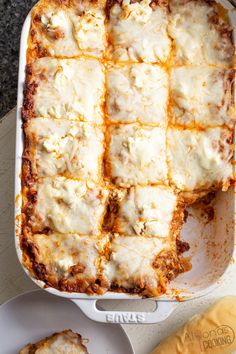 lasagna casserole with cheese and sauce in a white dish next to bread