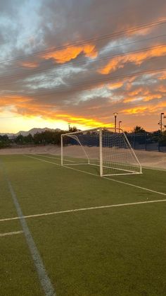 a soccer field with a goal and the sun setting