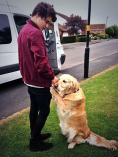 a man is petting his dog on the grass