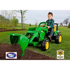 a young boy riding on the back of a green tractor