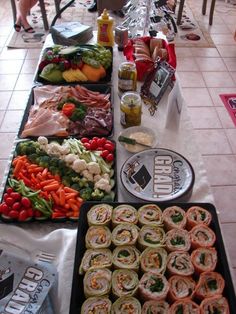 several trays filled with different types of food on top of a white table cloth