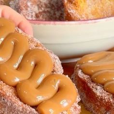 two donuts with chocolate frosting on them next to a bowl of doughnuts