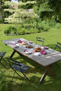 a picnic table set up with plates and cups on it in the middle of a grassy area