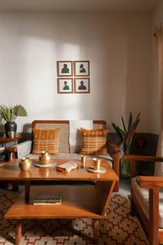 a living room with two couches, coffee table and potted plants in the corner