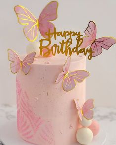 a pink birthday cake with gold butterflies on top and the words happy birthday written on it