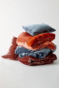 four pillows stacked on top of each other in different colors and sizes, with one folded down