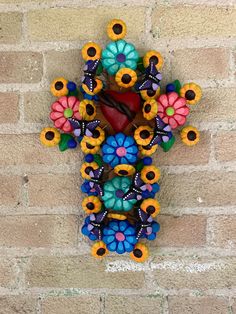 a clock made out of beads and flowers on a brick wall with a red heart in the middle