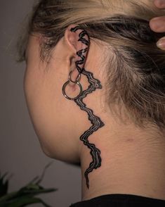 a woman with a tattoo on her neck and behind the ear is a snake design