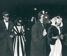 an old black and white photo of people dressed up in costumes with masks on their faces