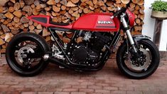 a red motorcycle parked next to a pile of logs