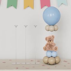 a teddy bear sitting on top of balloons in front of a wall with bunting