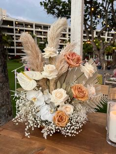 a vase filled with flowers sitting on top of a wooden table next to a candle