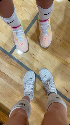 two people standing on a basketball court with their feet in the air and one person wearing white sneakers