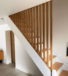 a wooden stair case next to a white wall