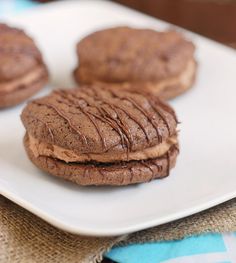 three chocolate cookies are on a white plate