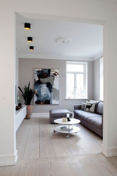 a living room filled with furniture and a painting on the wall above it's windows