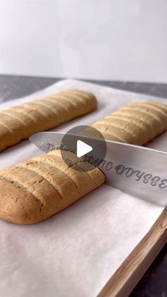 two loaves of bread sitting on top of a cutting board next to a knife