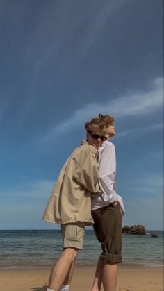 two people are standing on the beach near the water