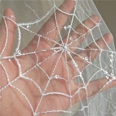 someone is holding their hand in front of a net with spider webs on it