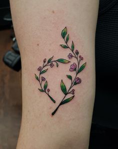 a small tattoo on the leg of a woman's arm with leaves and flowers